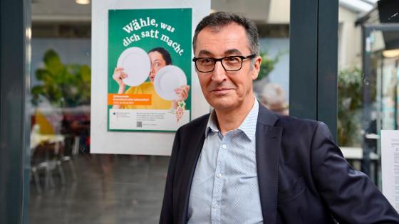 Bundesminister Özdemir steht vor einem Plakat mit der Überschrift "Wähle, was dich satt macht.