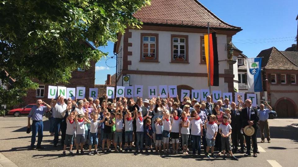 Gruppe von Menschen, die am 26. Bundeswettbewerb "Unser Dorf hat Zukunft" teilgenommen haben; Schriftzug: Unser Dorf hat Zukunft 