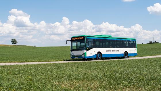 Bus fährt auf einer kleinen Straße durch Felder